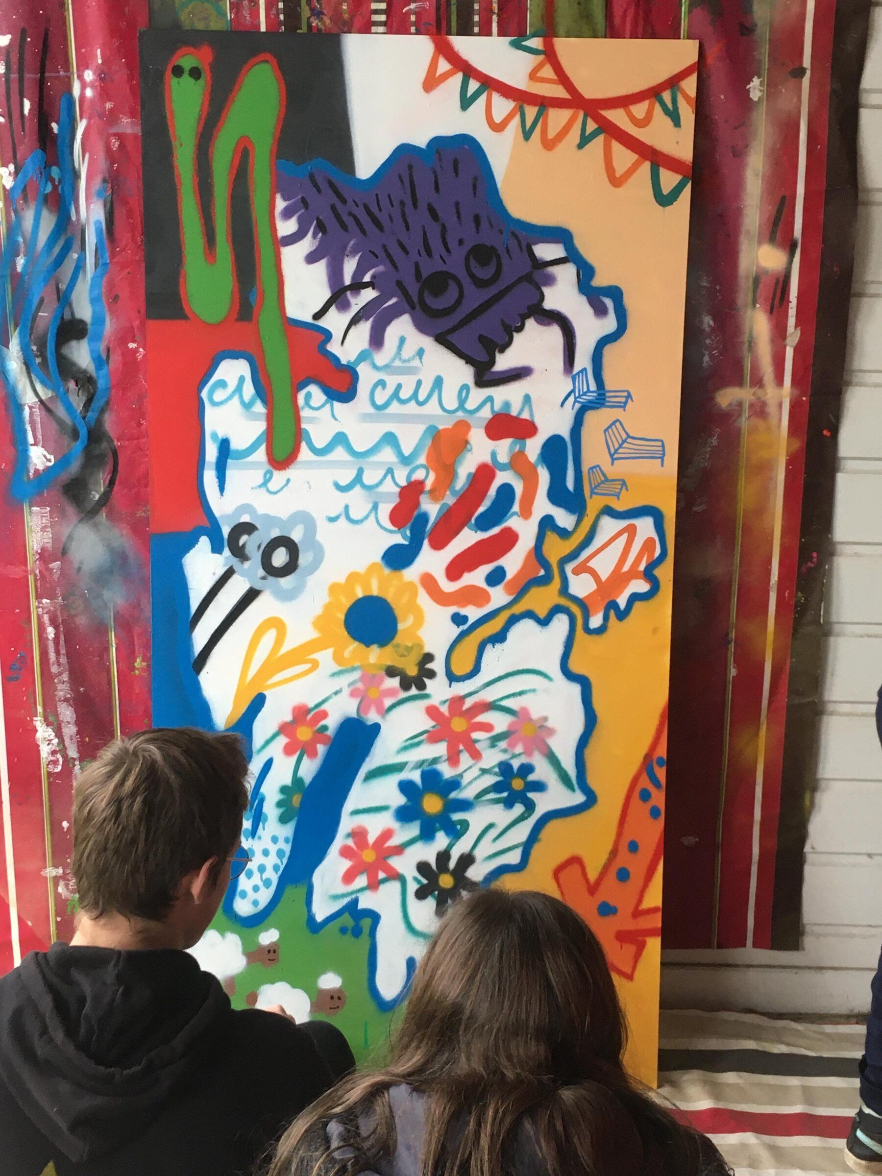 Participants de dos devant une peinture collective