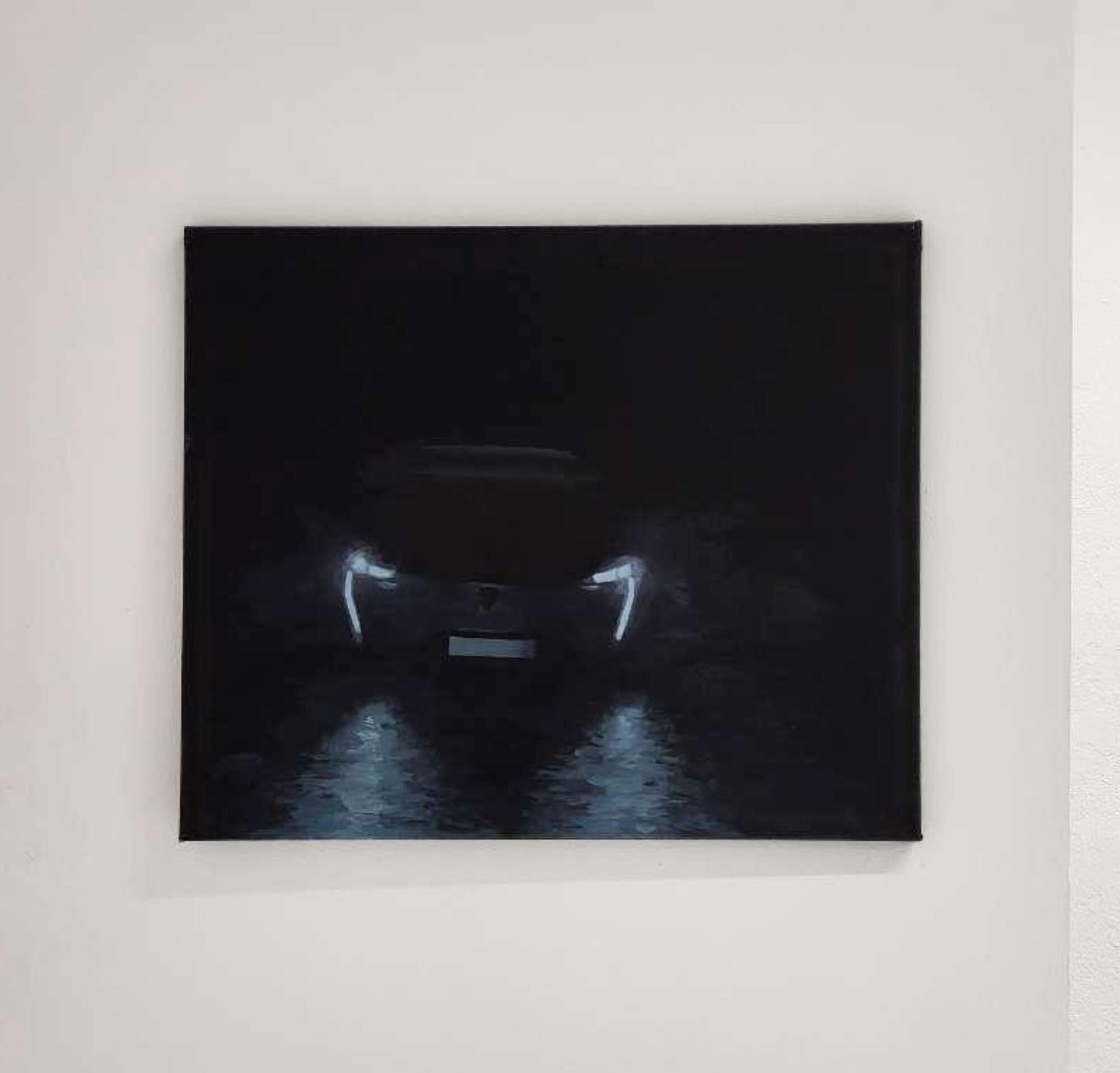 Toile sombre : les phares d'une voiture dans la nuit, reflétés sur le sol mouillé