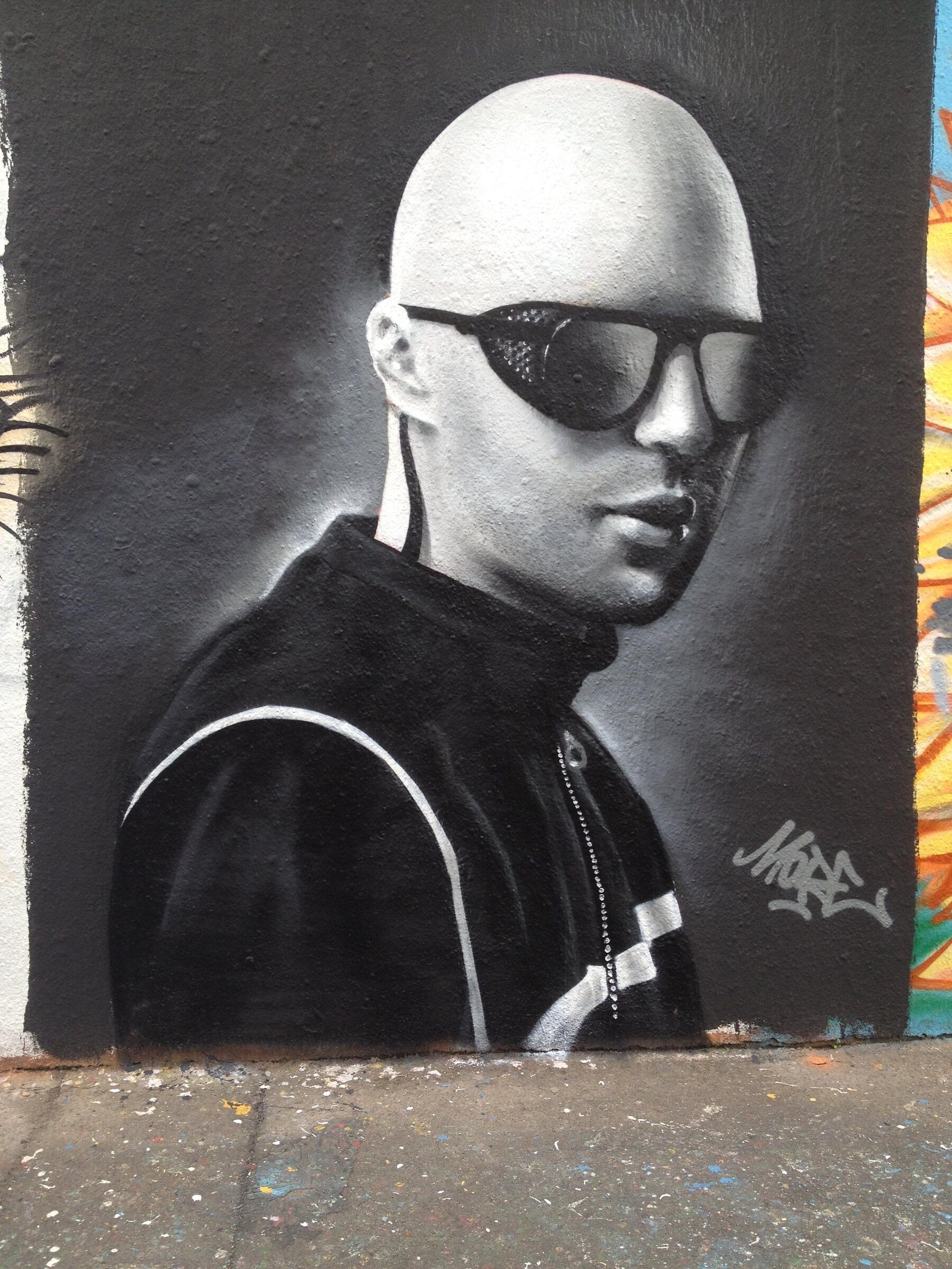 Portrait en noir et blanc d'un homme au crâne rasé et lunettes de soleil