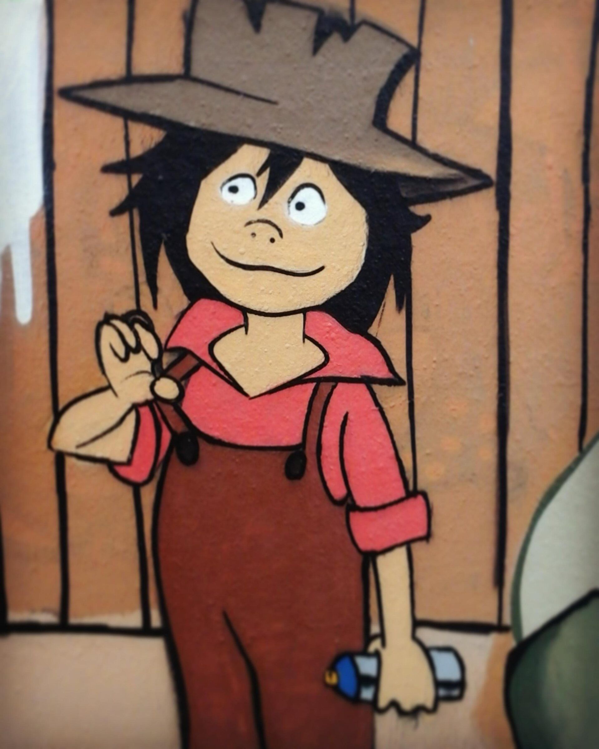 Tom Sawyer en salopette, chapeau et bombe de peinture à la main